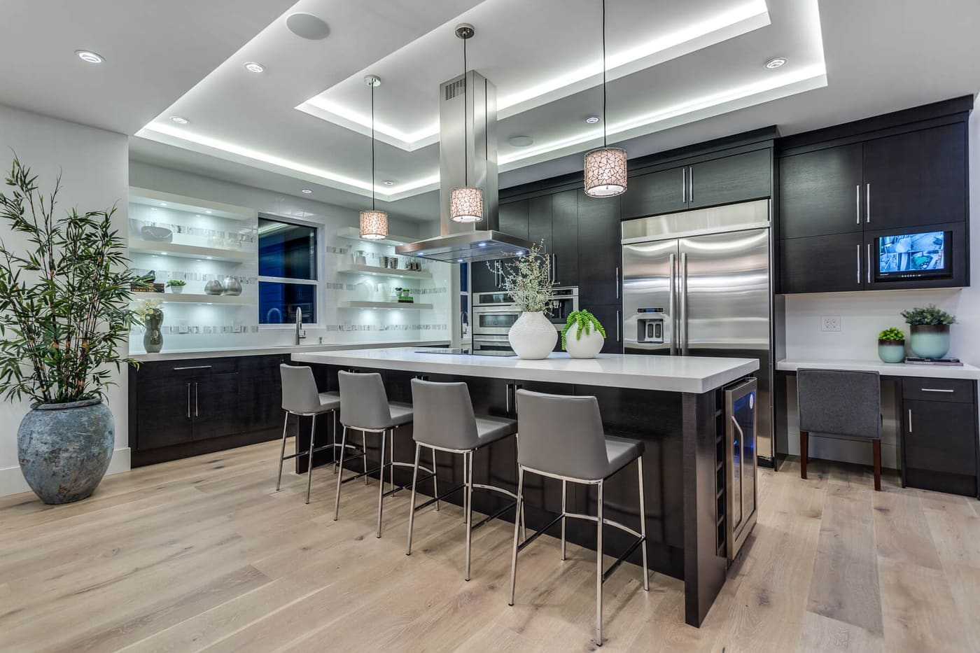 Kitchen with dark cabinetry, a waterfall island, and recessed cove lighting