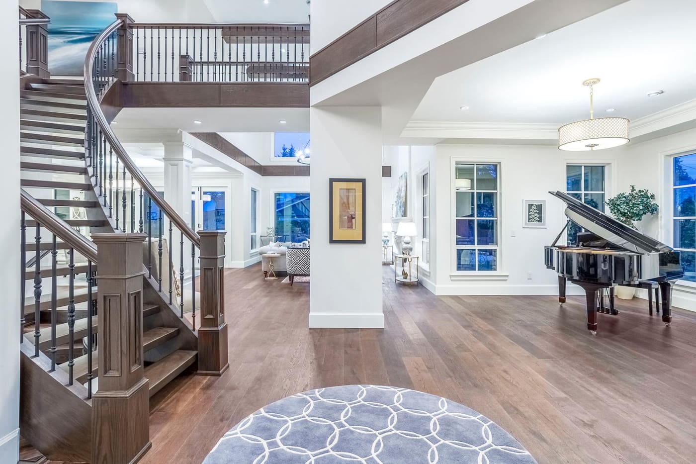 Entry hall with a curved wood staircase and a grand piano in the adjoining room