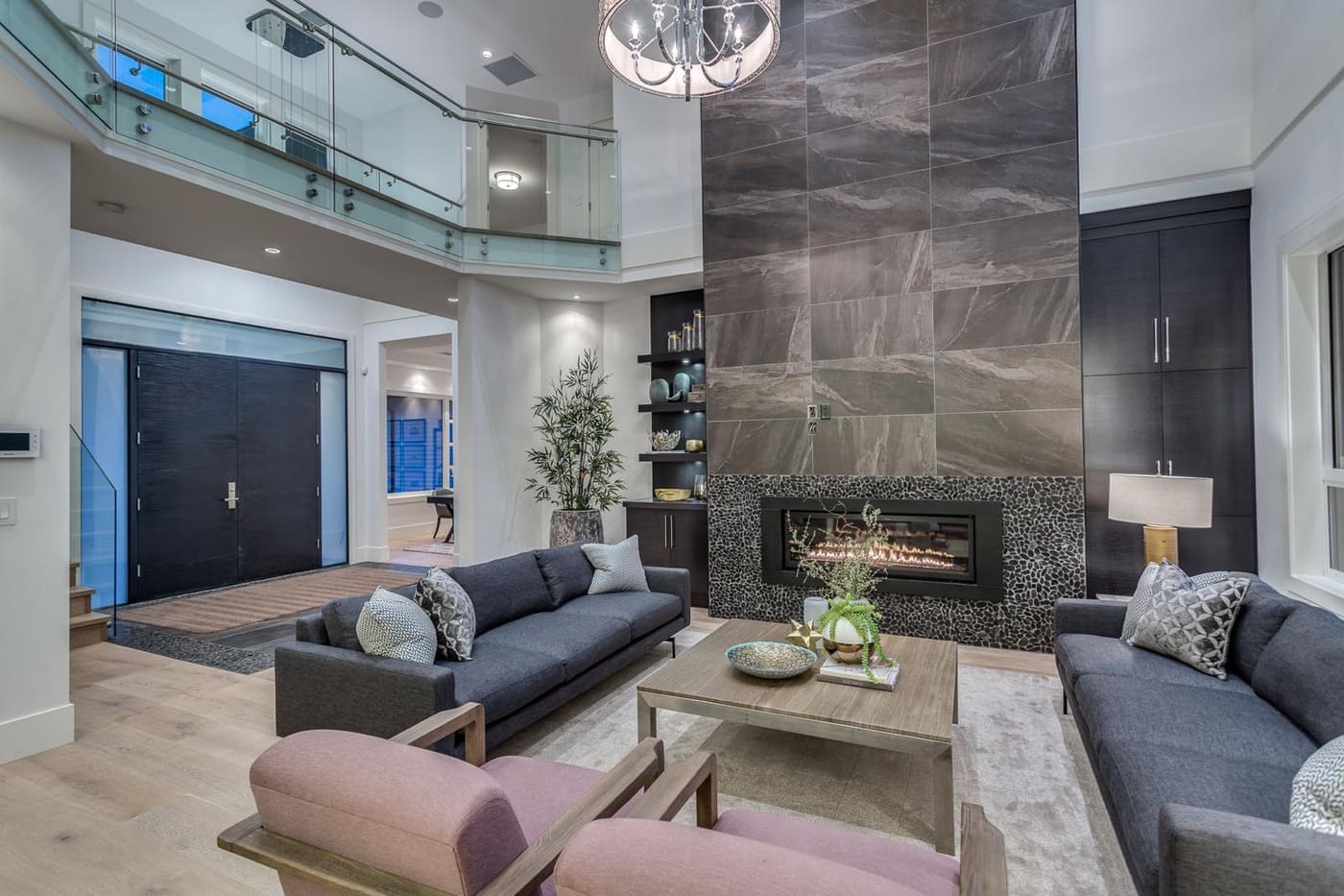 Double-height living room with a stone fireplace wall and glass mezzanine railing